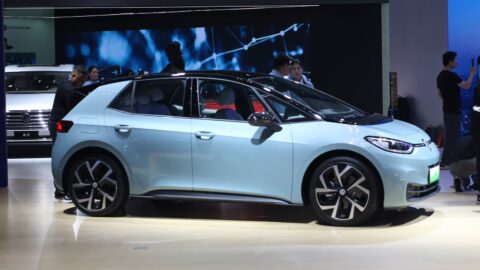 Volkswagen elektrikli araç üretim hattı, robotik kollar beyaz bir araç gövdesi üzerinde çalışıyor.