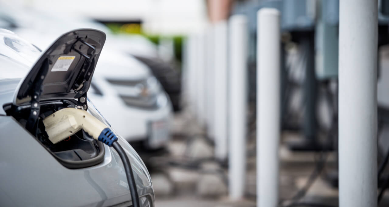 Elektrikli araç şarj istasyonunun yanında büyük bir enerji depolama ünitesi, modern ve teknolojik görünüm