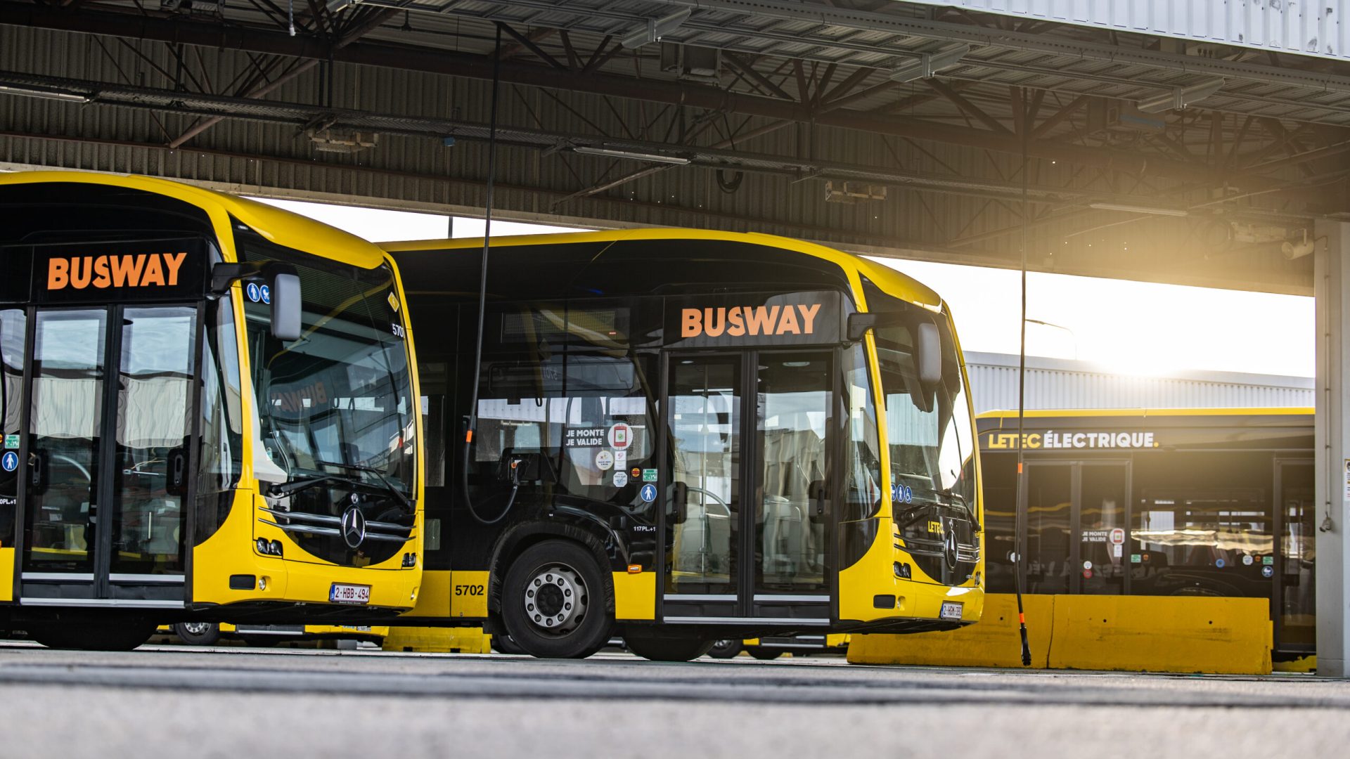 Bir otobüs deposunda sıralanmış elektrikli otobüsler ve şarj üniteleri, endüstriyel ortam
