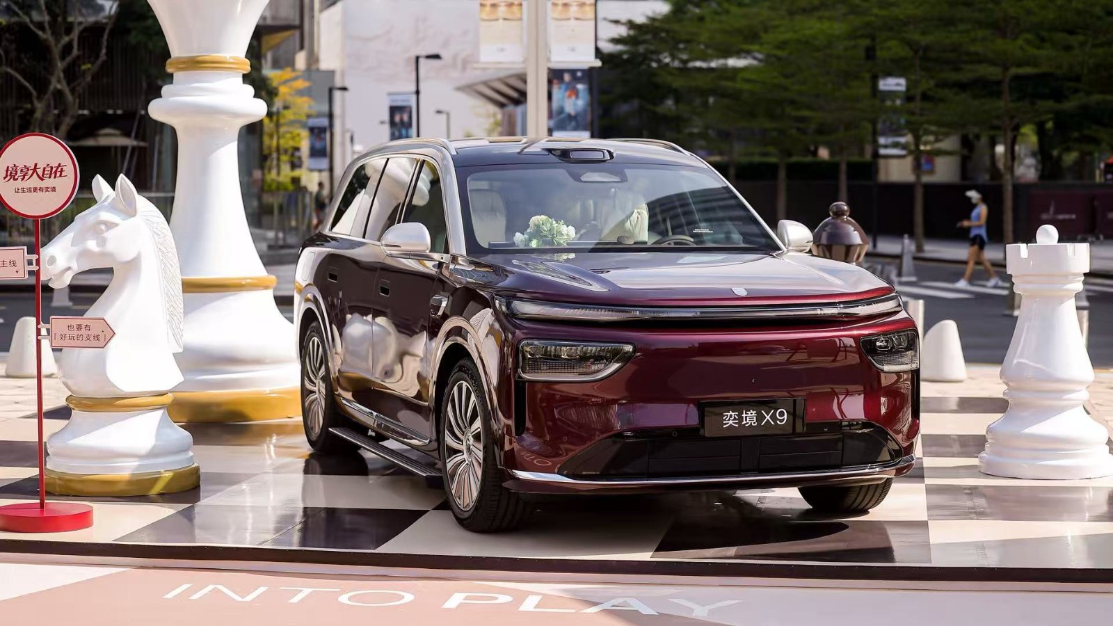 Otomatik batarya değişim istasyonunda bir elektrikli SUV aracı, mavi ortam ışıkları ve robotik kollar görünüyor