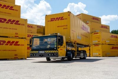 Elektrikli dağıtım araçlarından oluşan bir filo depoda şarj istasyonlarında park halinde