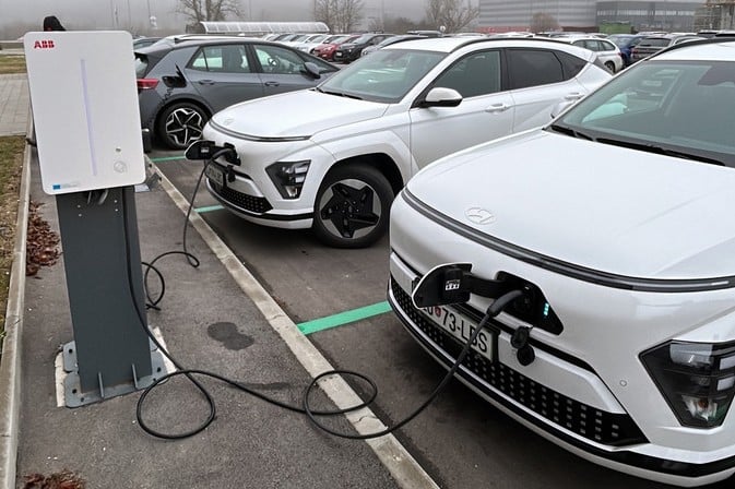 CCS bağlantılı bir elektrikli otomobilin çift yönlü şarj istasyonuna bağlanmış hali, arka planda güneş panelleri ve ev görünüyor.