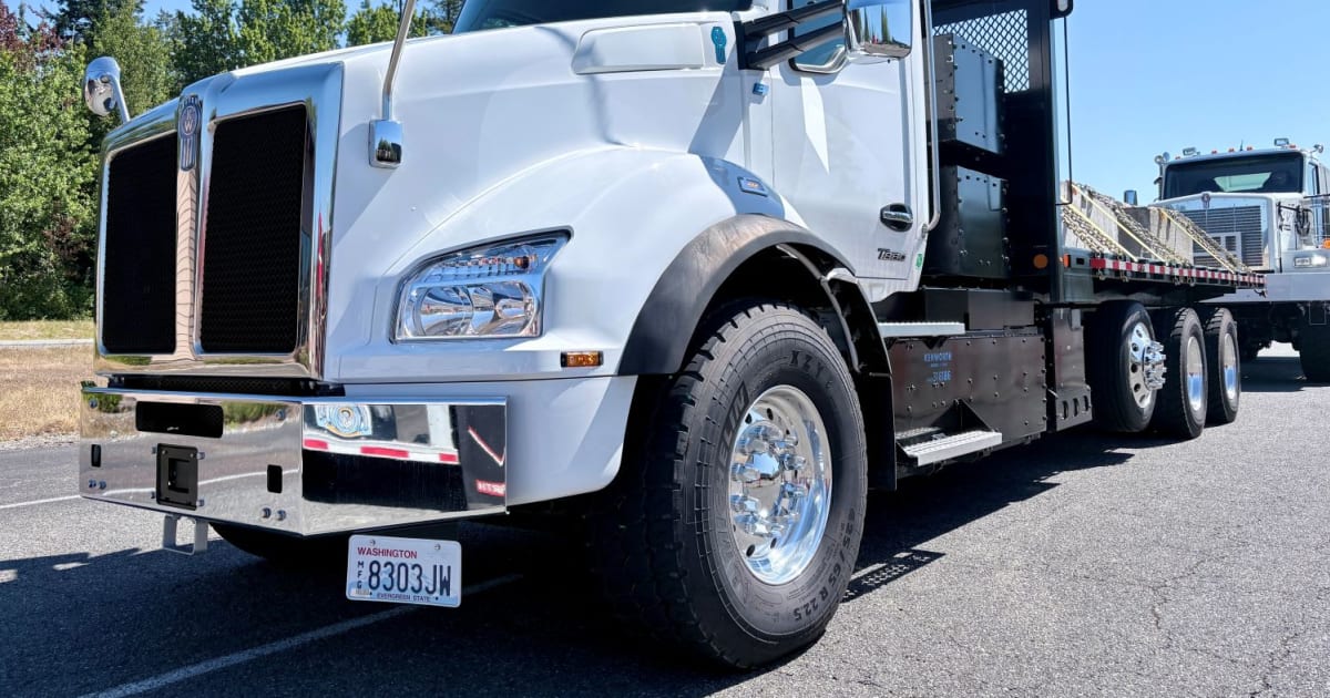 Kenworth T880E elektrikli kamyon, bir şantiye alanında DC hızlı şarj cihazına bağlı duruyor.