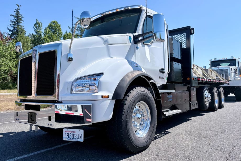 Kenworth T880E elektrikli kamyon, bir şantiye alanında DC hızlı şarj cihazına bağlı duruyor.