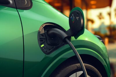 Bir kamyon durağında, büyük bir elektrikli kamyonun yüksek güçlü bir şarj ünitesine bağlandığı genel görünüm.