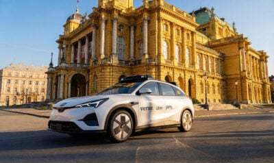 Bir lamba direğine monte edilmiş kuş yuvası şeklinde ödeme terminali ve yanında elektrikli araç şarj istasyonu, gündüz, açık hava