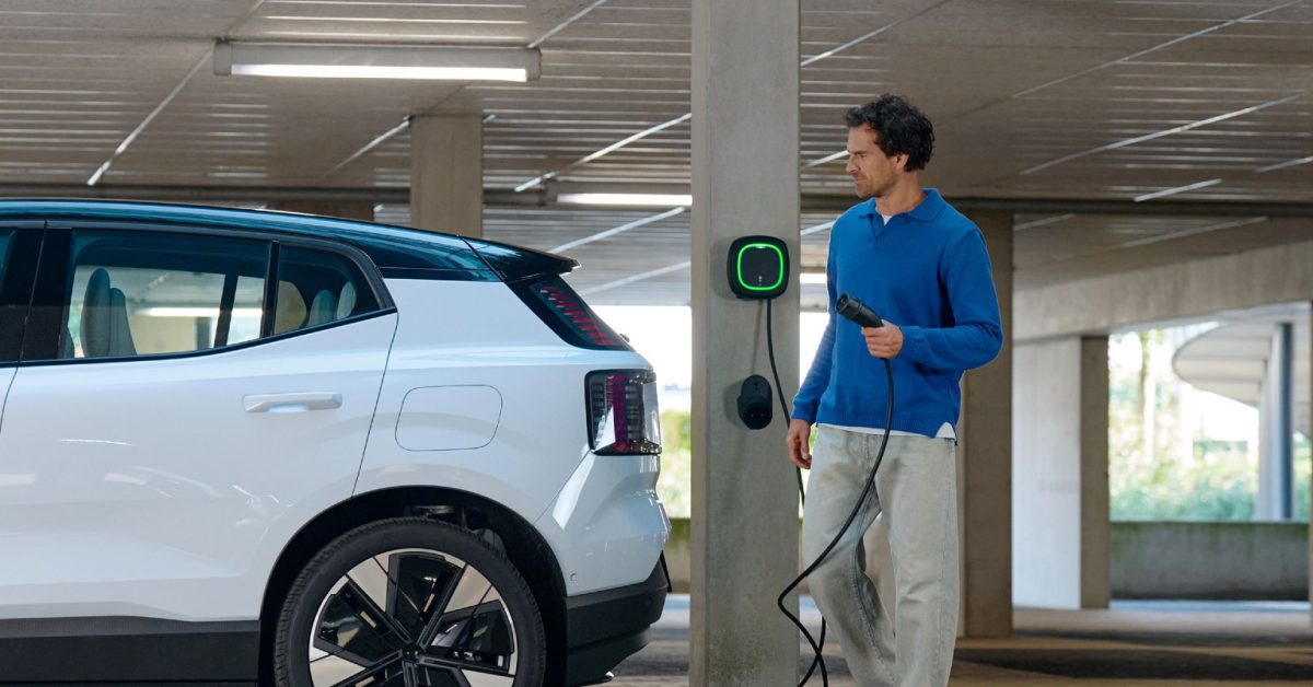 Havalimanı otoparkında elektrikli araçların şarj olduğu bir görüntü, arka planda uçak.