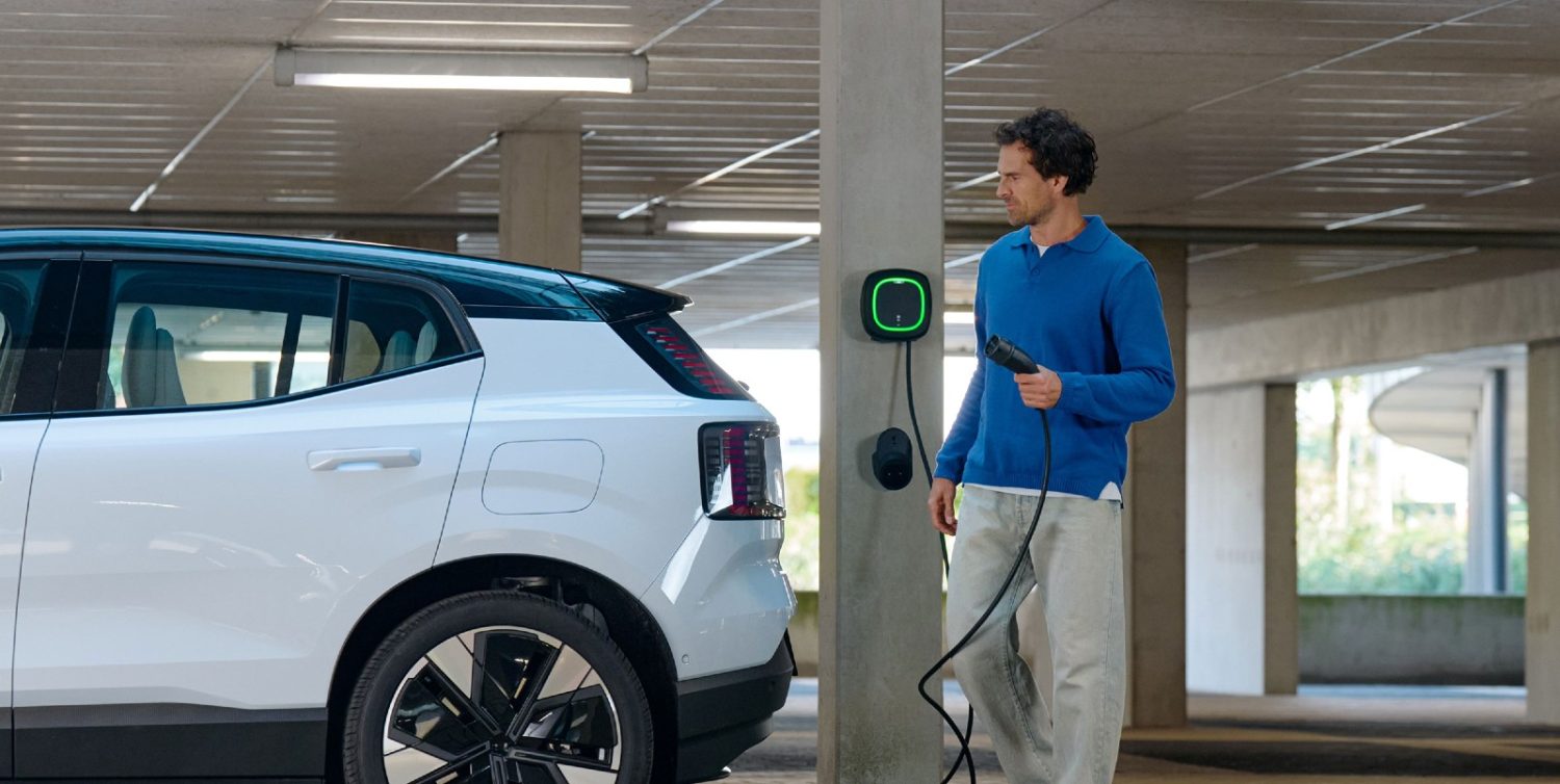 Havalimanı otoparkında elektrikli araçların şarj olduğu bir görüntü, arka planda uçak.