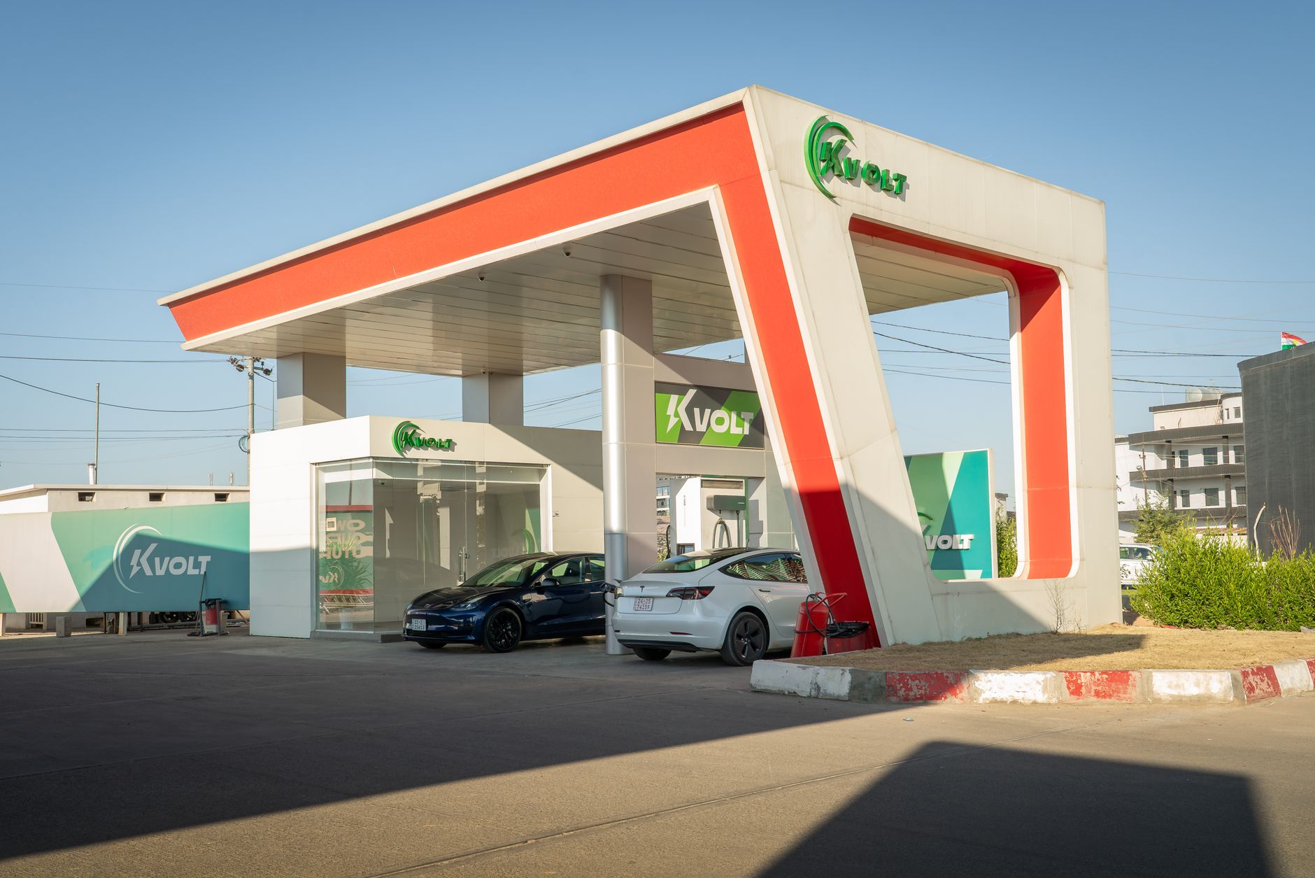 Bir elektrikli otomobilin yanında modern bir megavat şarj istasyonu, gece aydınlatması, geniş açı